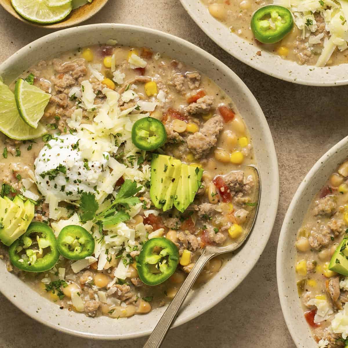 Turkey chili in a bowl with jalapenos, avocado and limes.