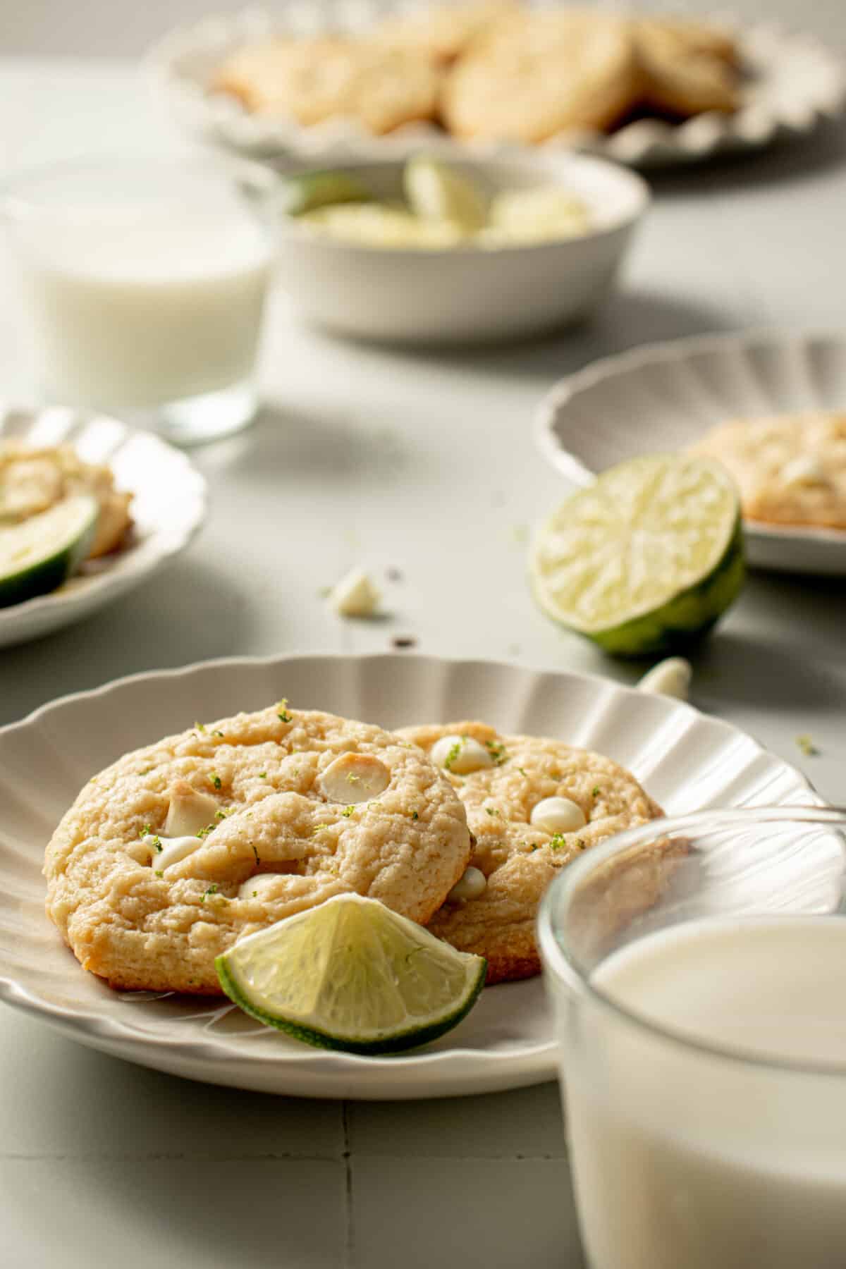 Cookies plated with limes around and a glass of milk. 