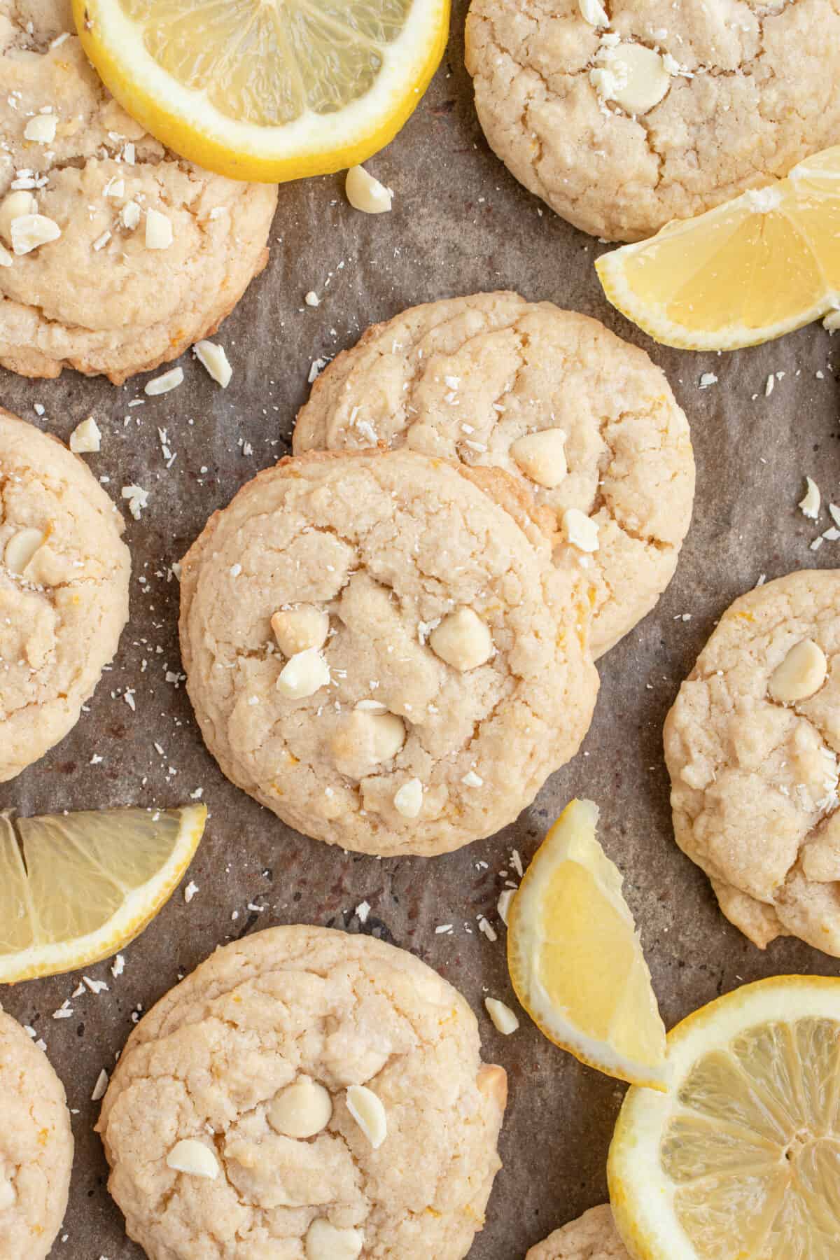 Lemon white chocolate cookies laid out with lemons. 
