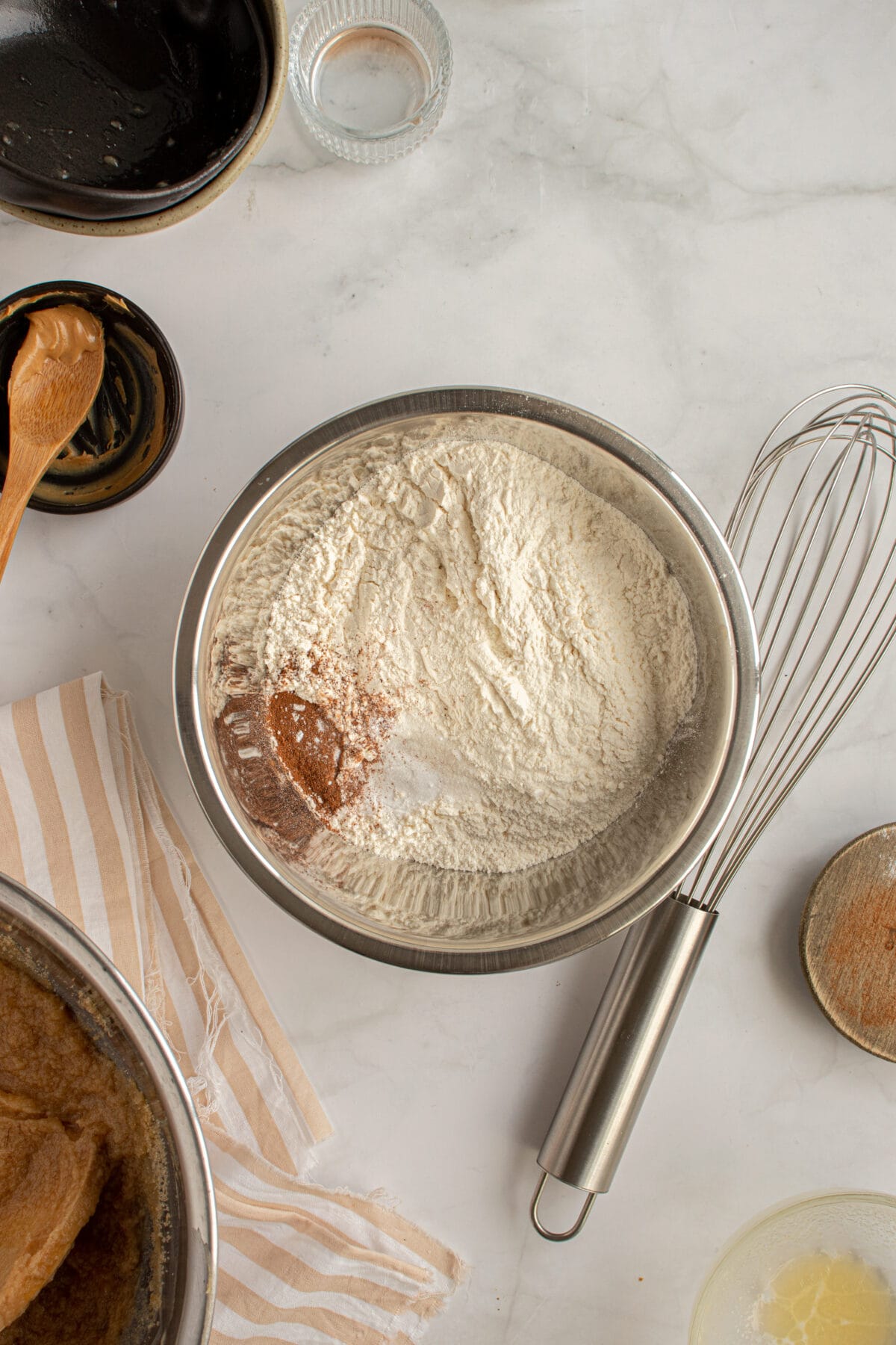 Dry ingredients in a metal bowl next to a whisk.