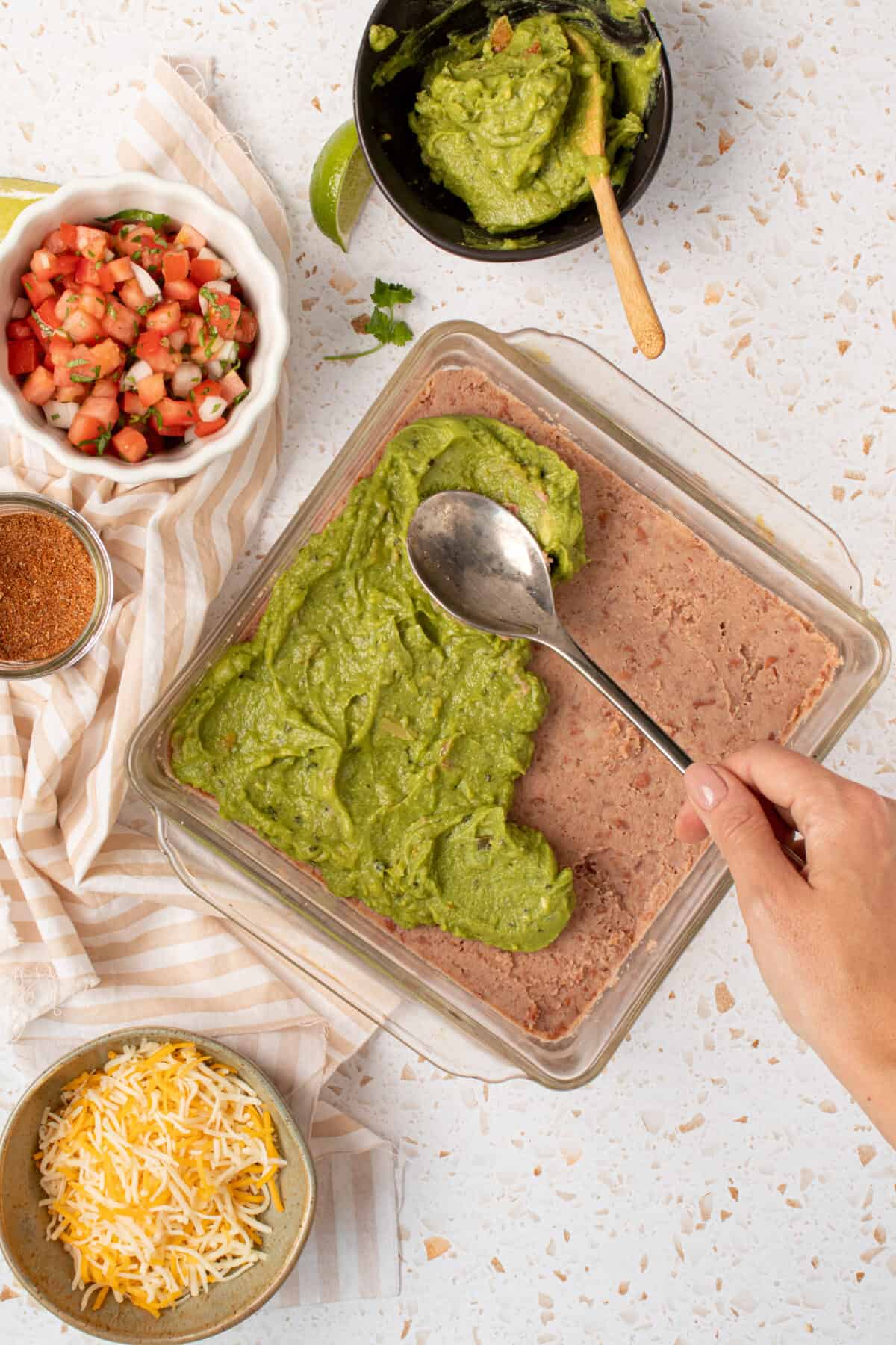 Spoon topping refried beans with guacamole.