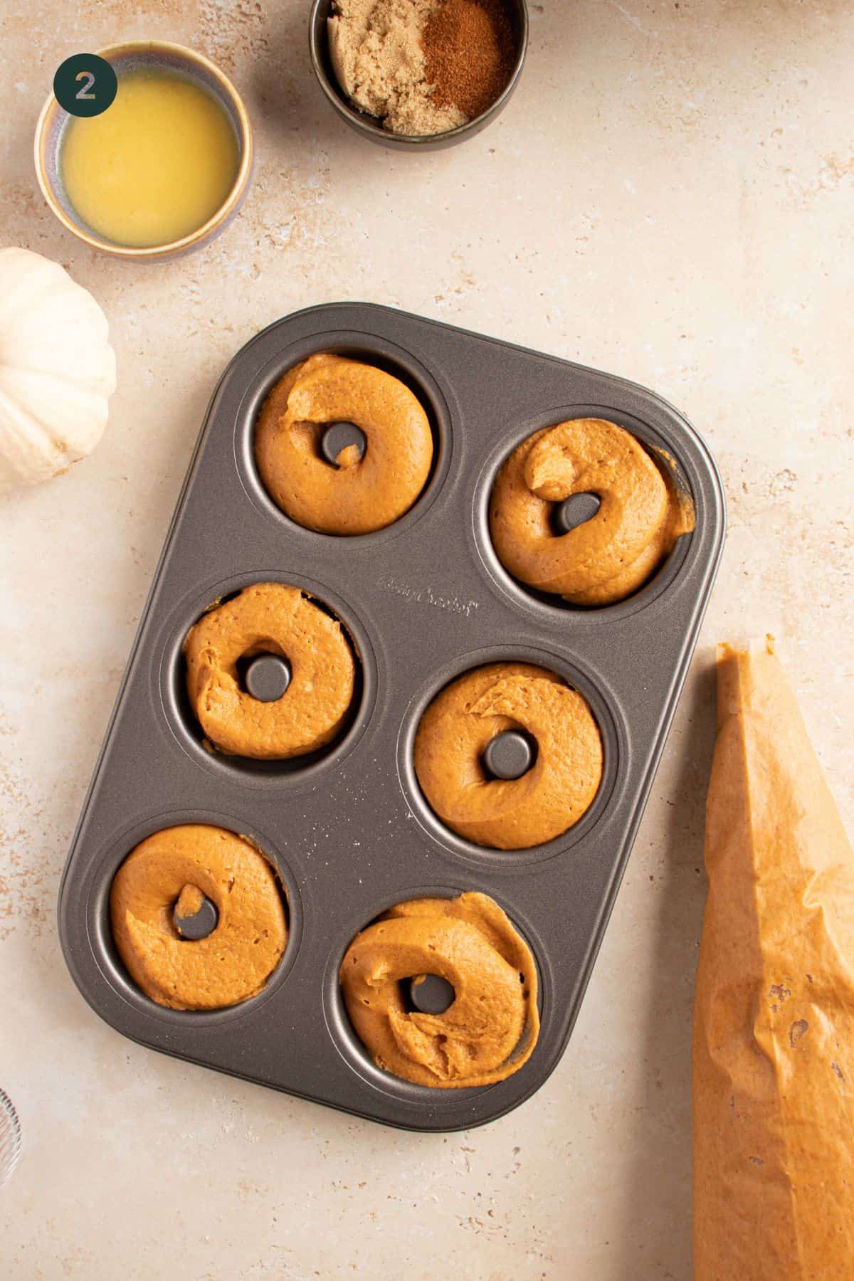 Piped donut butter in a donut pan. 