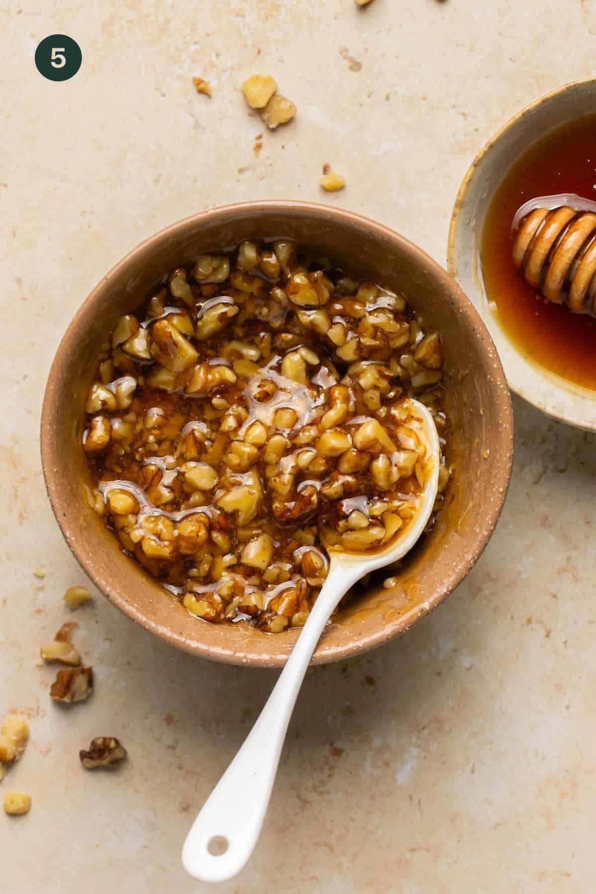 Chopped walnuts and honey combined in a small mixing bowl. 