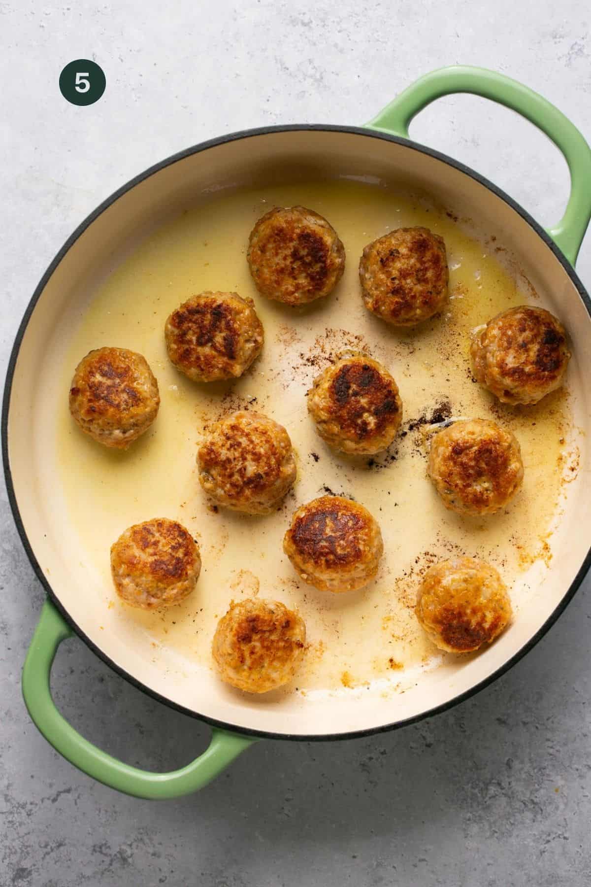 Browned meatballs in a pan. 