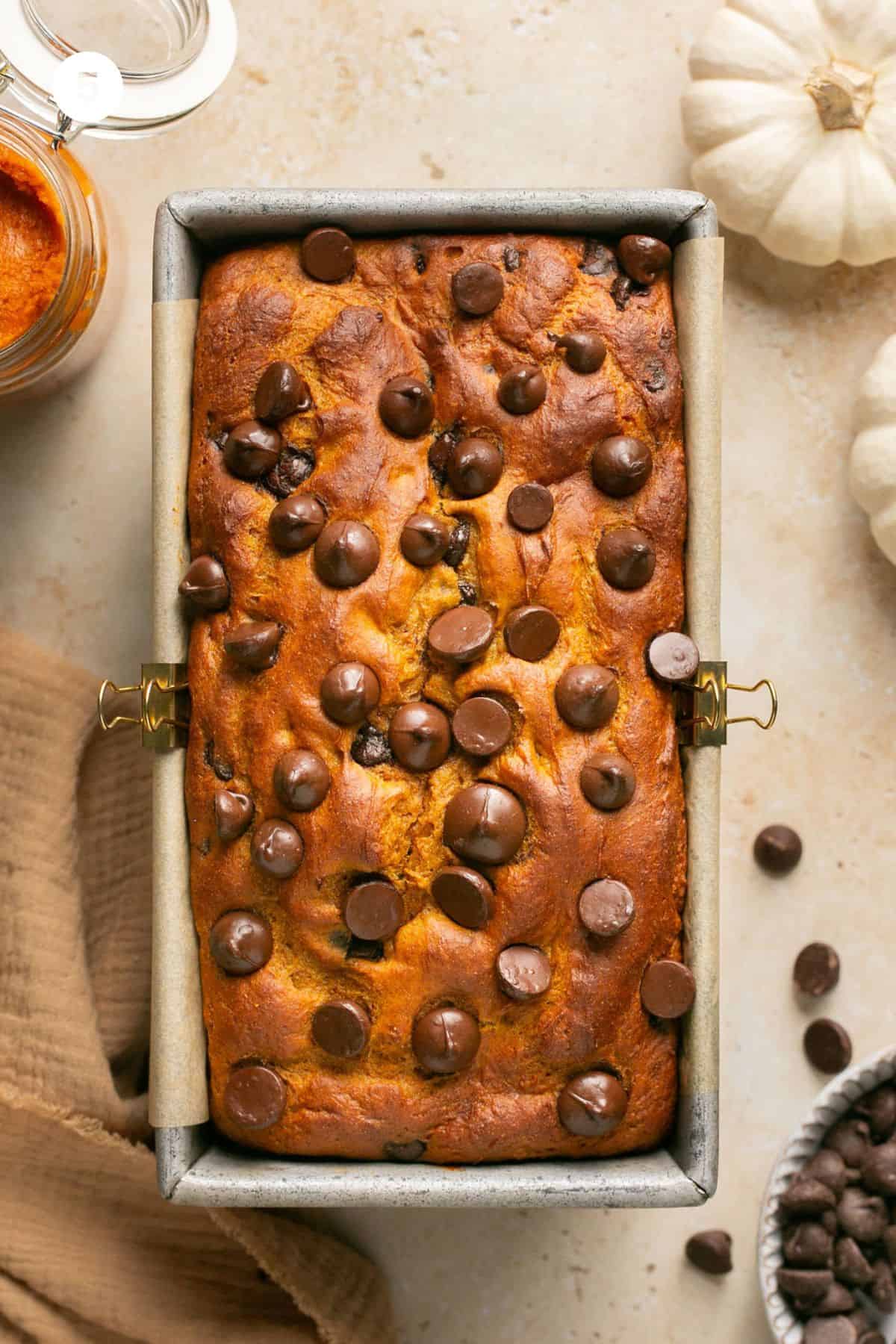 Baked brown topped bread with chocolate chips on top in the load pan. 