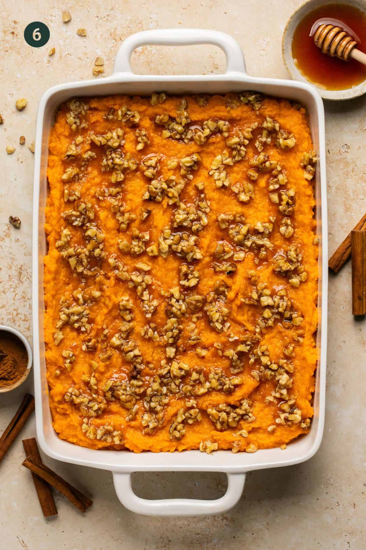 Baking dish with mashed sweet potatoes layered on the bottom and topped with the walnut honey mixture spread over the top in chunks. 