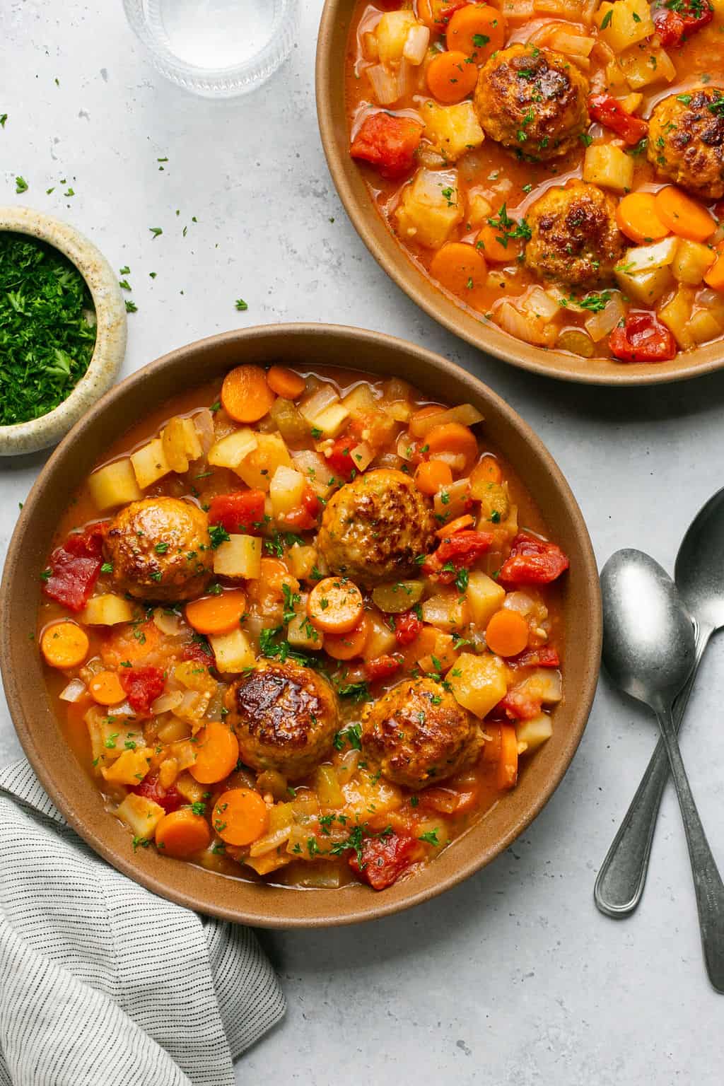 Two bowls of stew with parsley on top. 