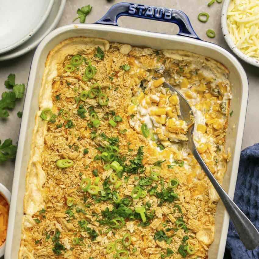 Creamy corn casserole in a baking pan with green onions and cilantro on top.