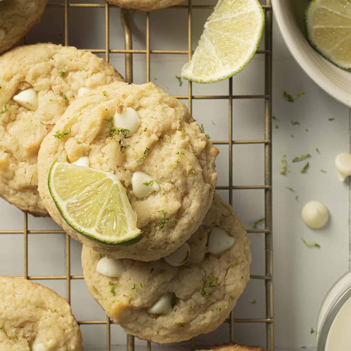 Cookies on a cooling rack with lime wedges and zest on top.
