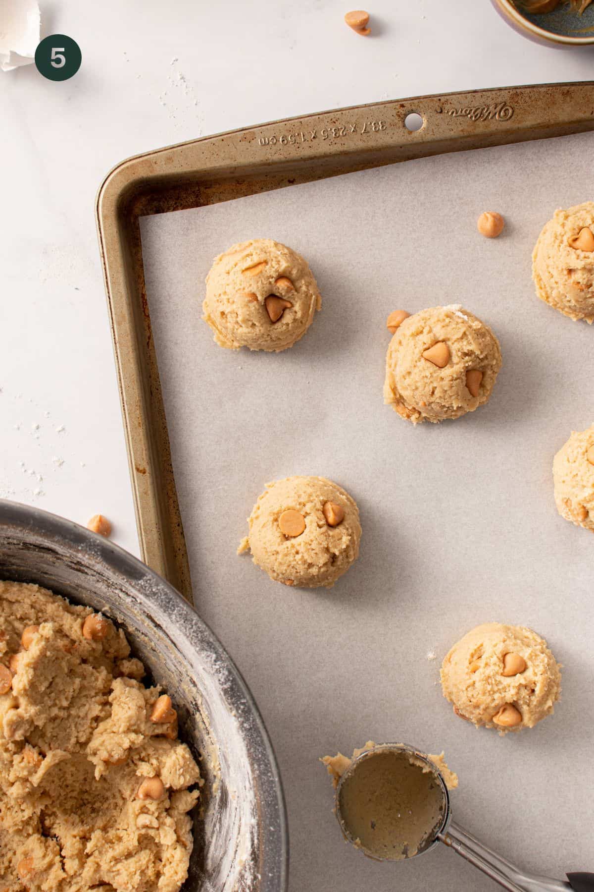 Cookie dough balls on a baking sheet ready to bake. 