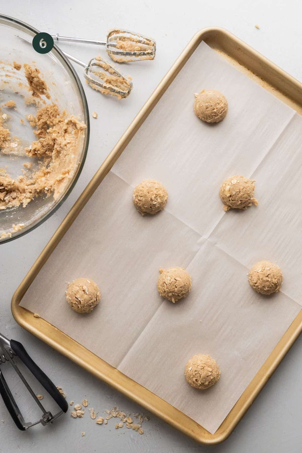 Cookie dough scooped out into balls on a cookie sheet.