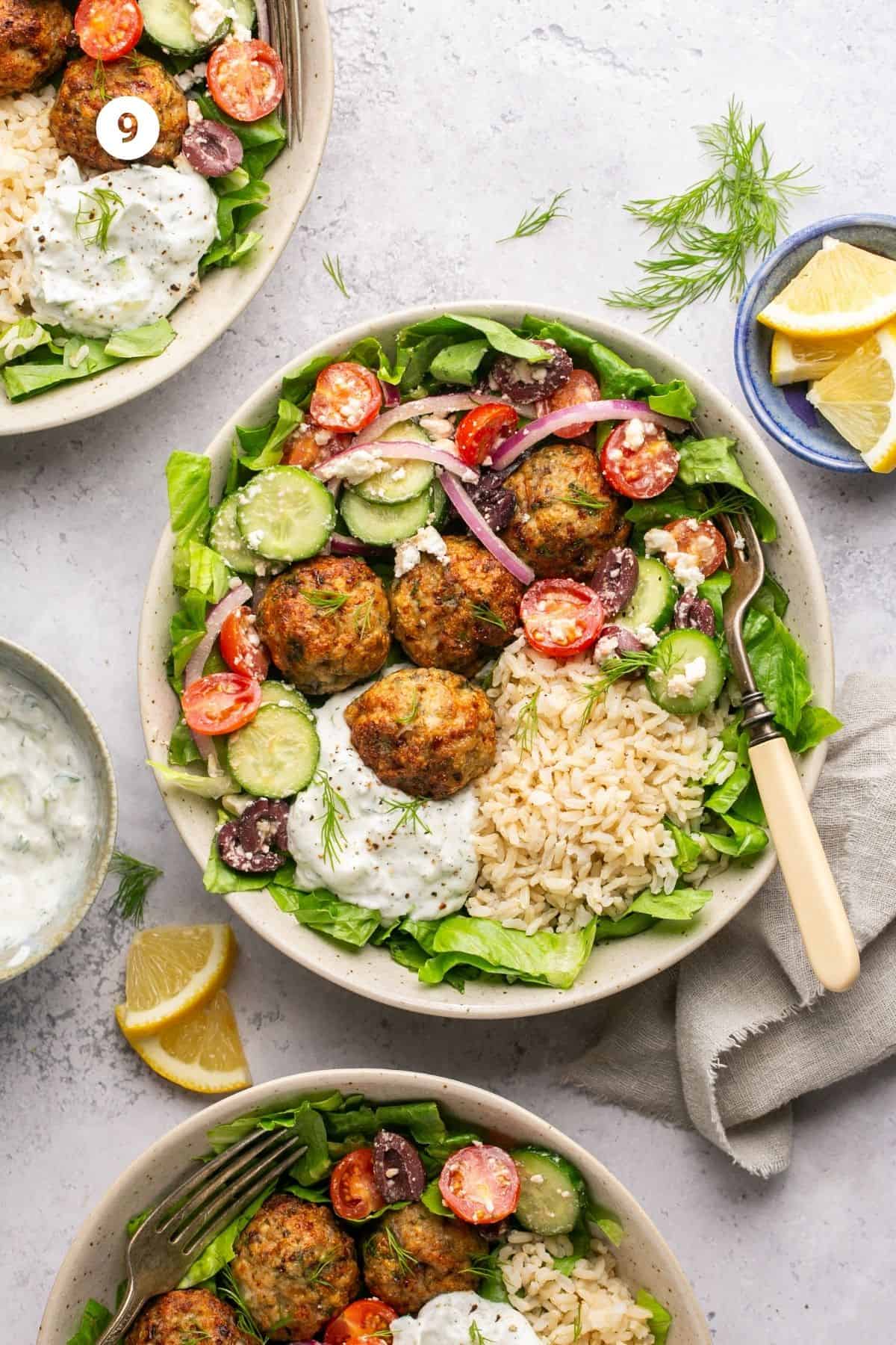 Bed of lettuce topped with brown rice, greek salad mixture, homemade tzatziki and meatballs. 