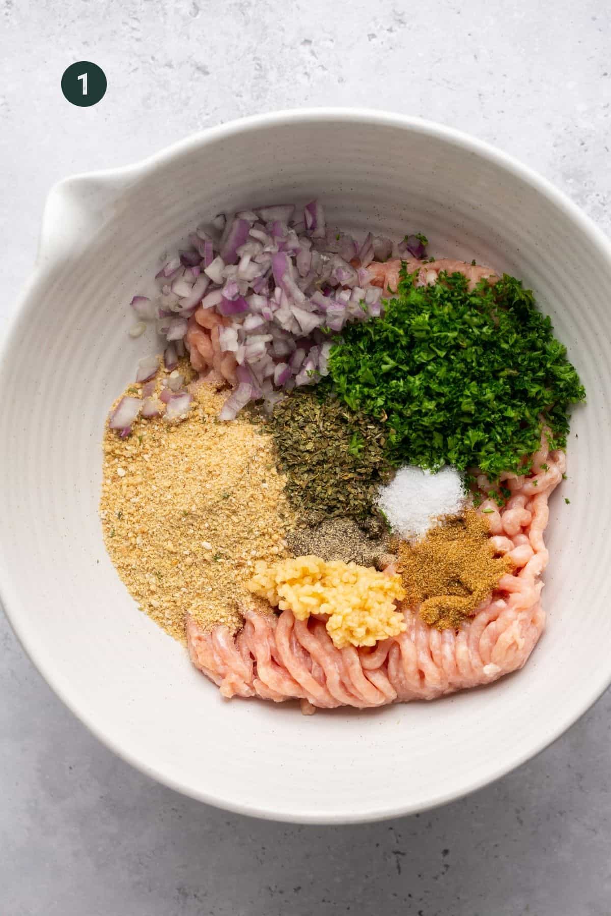 Ground chicken, spices, breadcrumbs and onions in a bowl. 