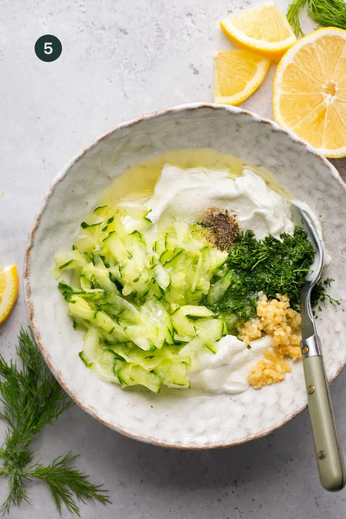 Cucumber, lemon, dill, yogurt and seasonings in a bowl. 