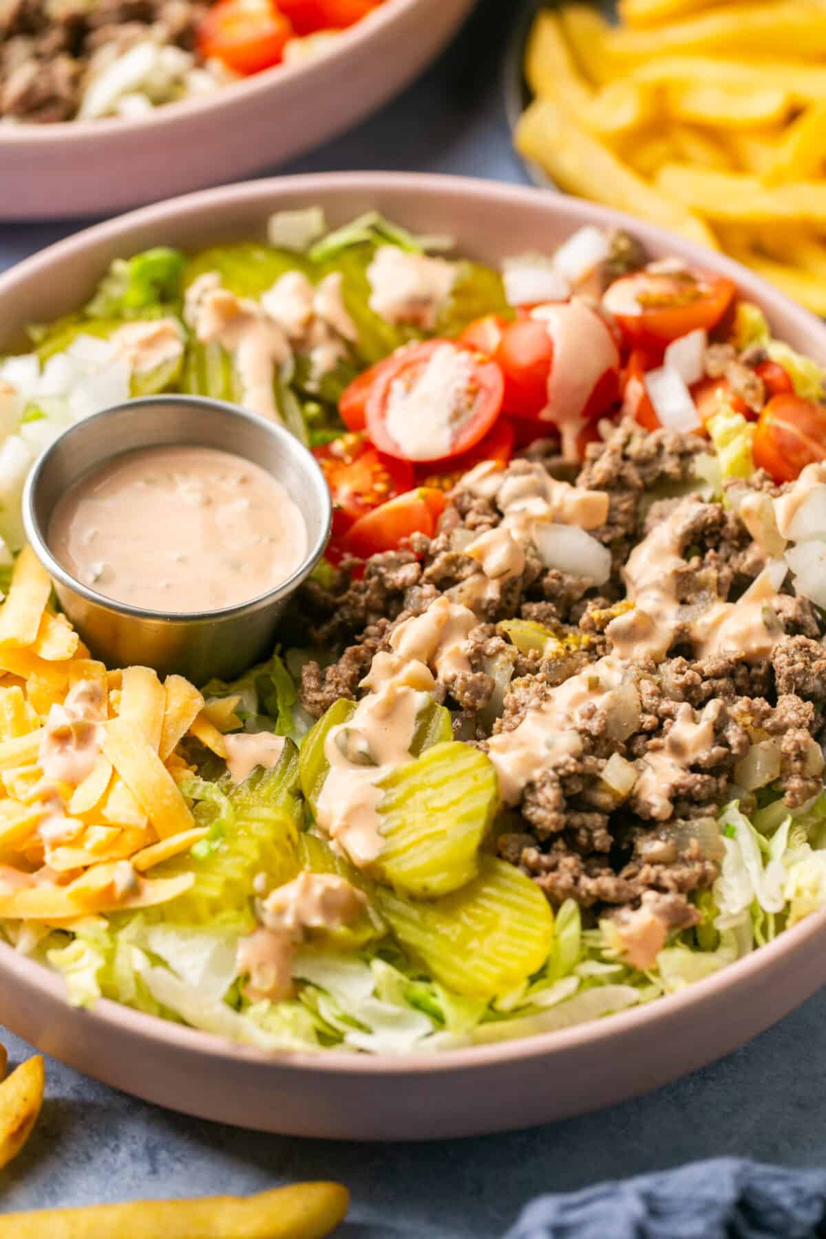 Assembles burger bowls with sauce on top and extra on the side. 