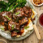 Sticky short ribs on a plate with mashed potatoes and broccoli.