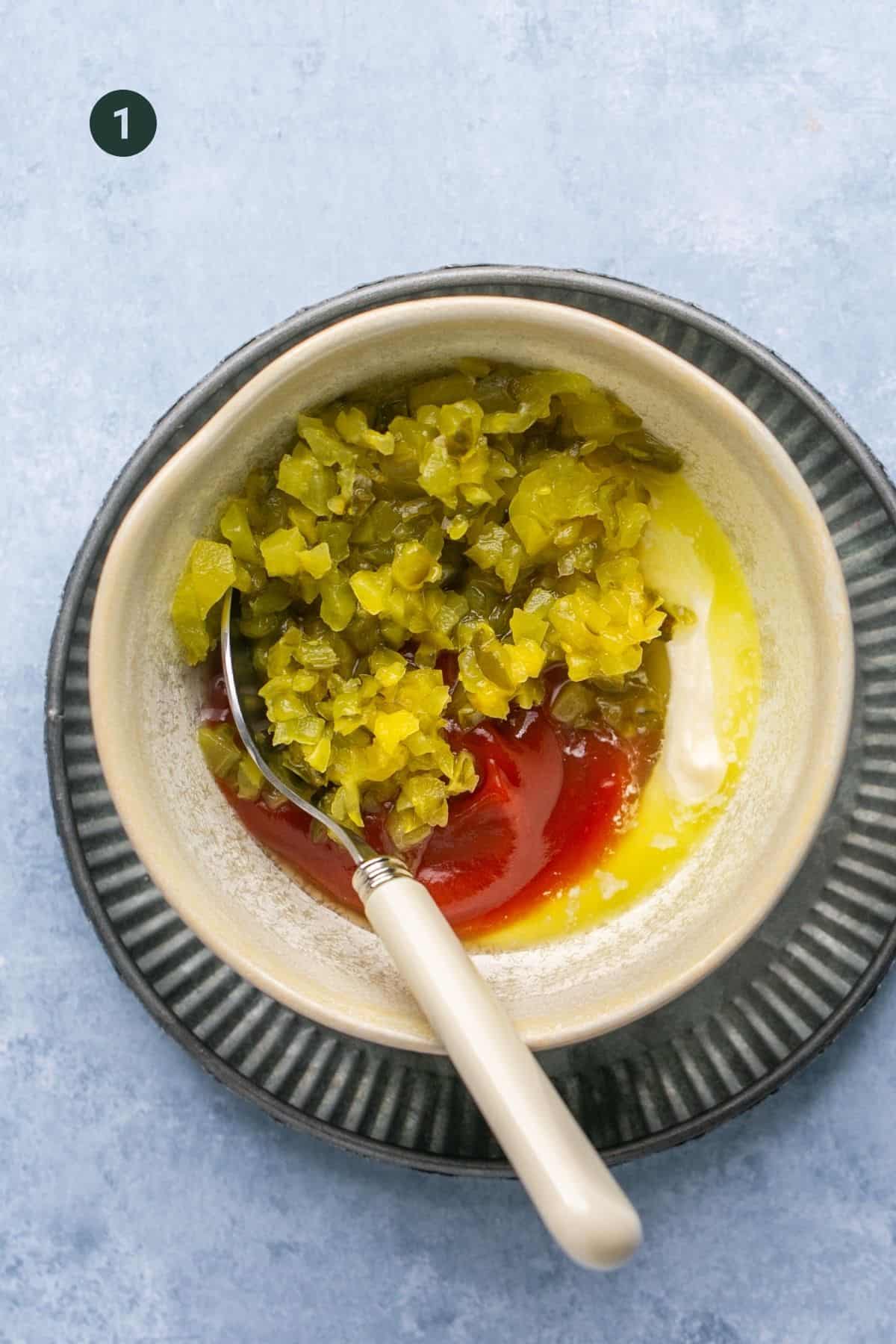Pickles, pickle juice, mayonnaise and ketchup in a small bowl. 