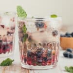 Blueberry mint drink with mint garnish and a straw.