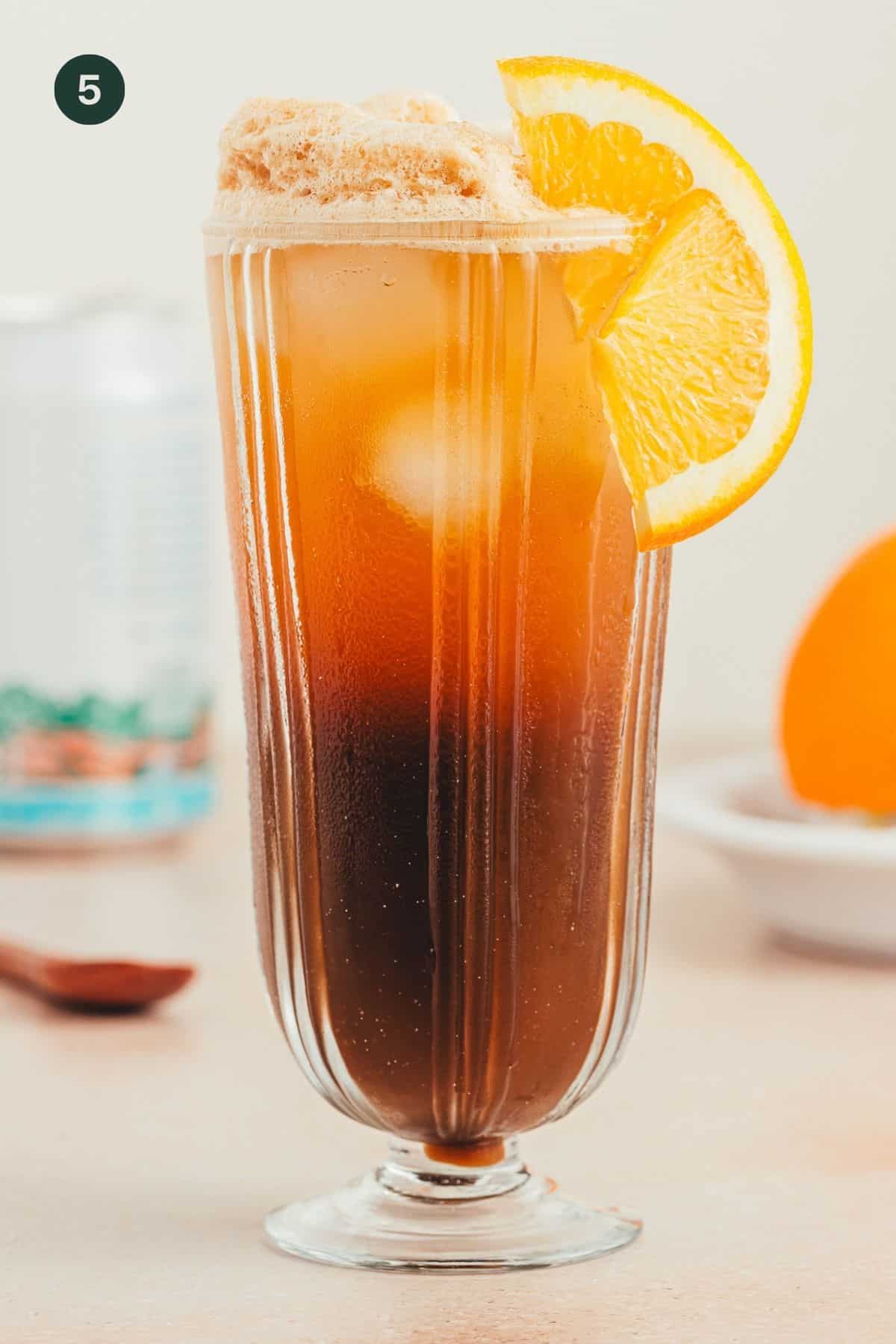 Coffee mocktail with orange slice as garnish in a tall glass. 