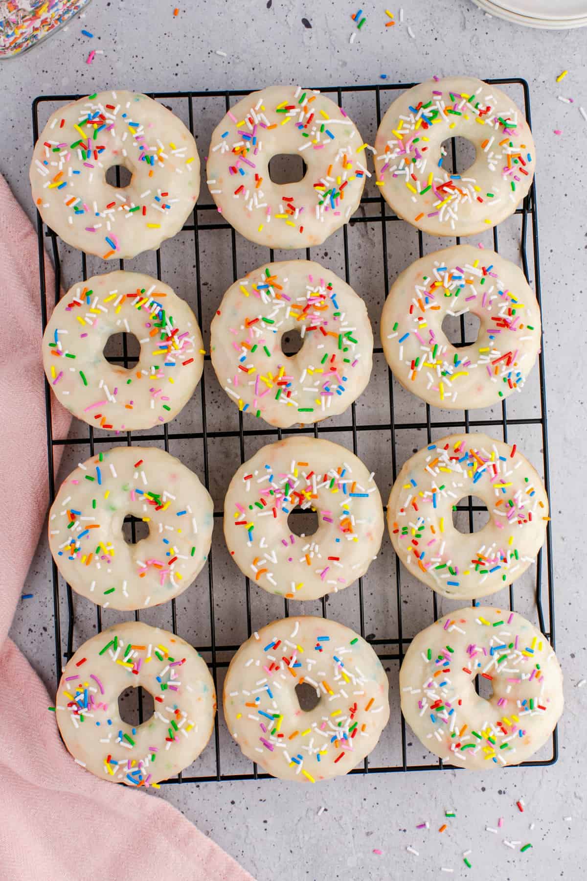 Wire rack with glazed donut on top with sprinkles. 