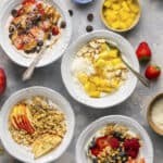 Peanut butter chocolate, tropical, apple pie and classic berry yogurt bowls made and ready to eat with spoons.