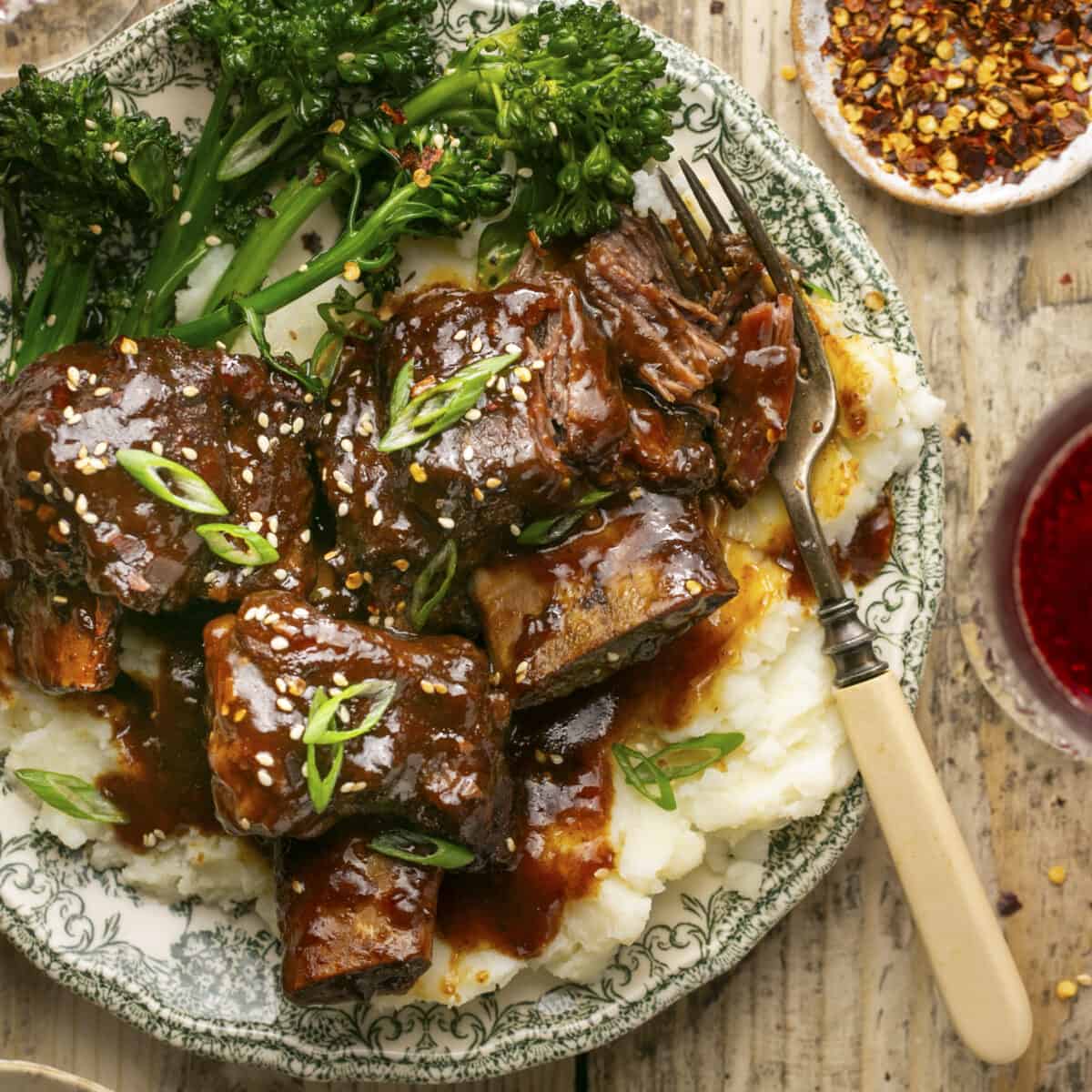 Sticky short ribs on a plate with mashed potatoes and broccoli.