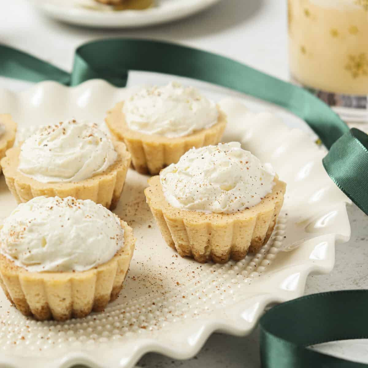Mini cheesecakes with whipped cream on top and a green ribbon laid out.