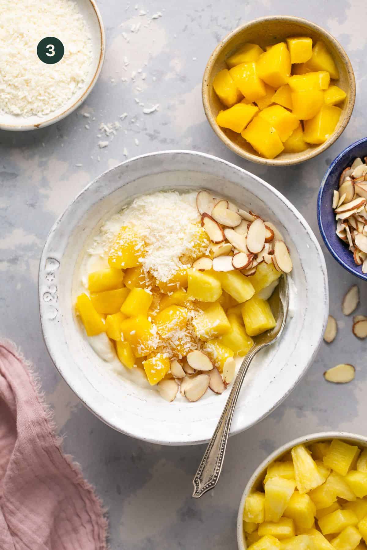 Pineapple, mango, sliced almonds and shredded coconut added on top of the yogurt bowl.