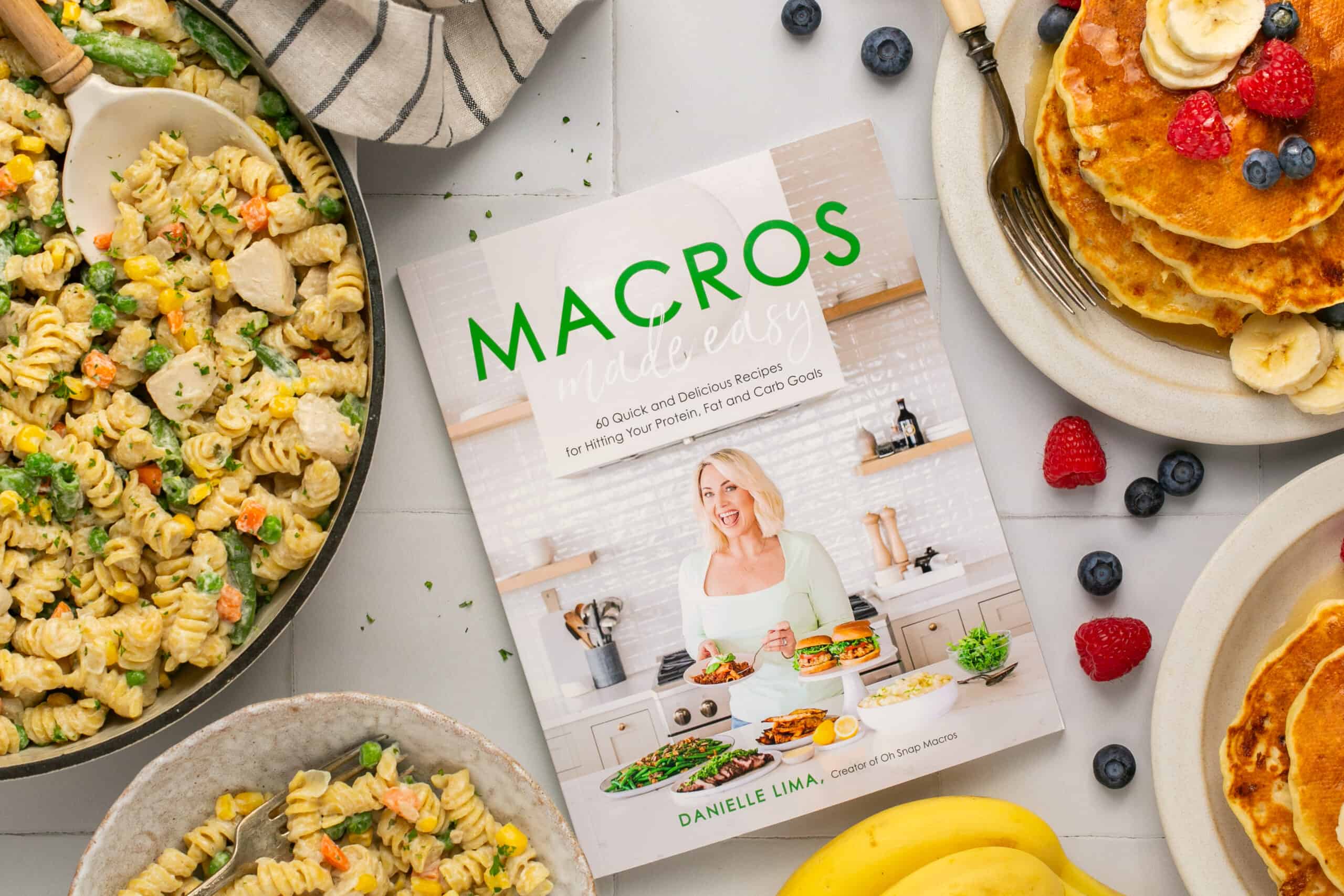 Cookbook, Macros Made Easy, surrounded by pancakes and pasta.