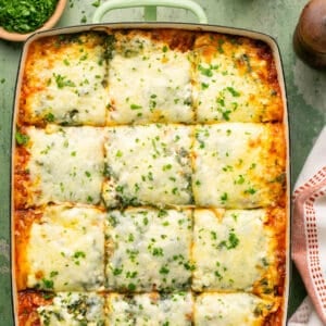 Lasagna with spinach in a baking dish cut into 12 squares.