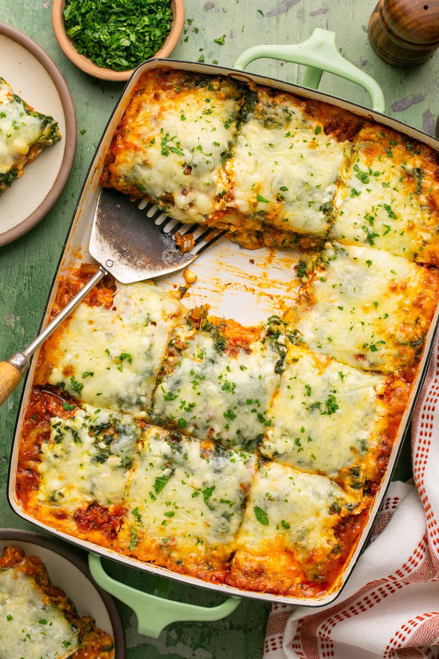 Lasagna cut into 12 squares with 2 out and plate nearby.