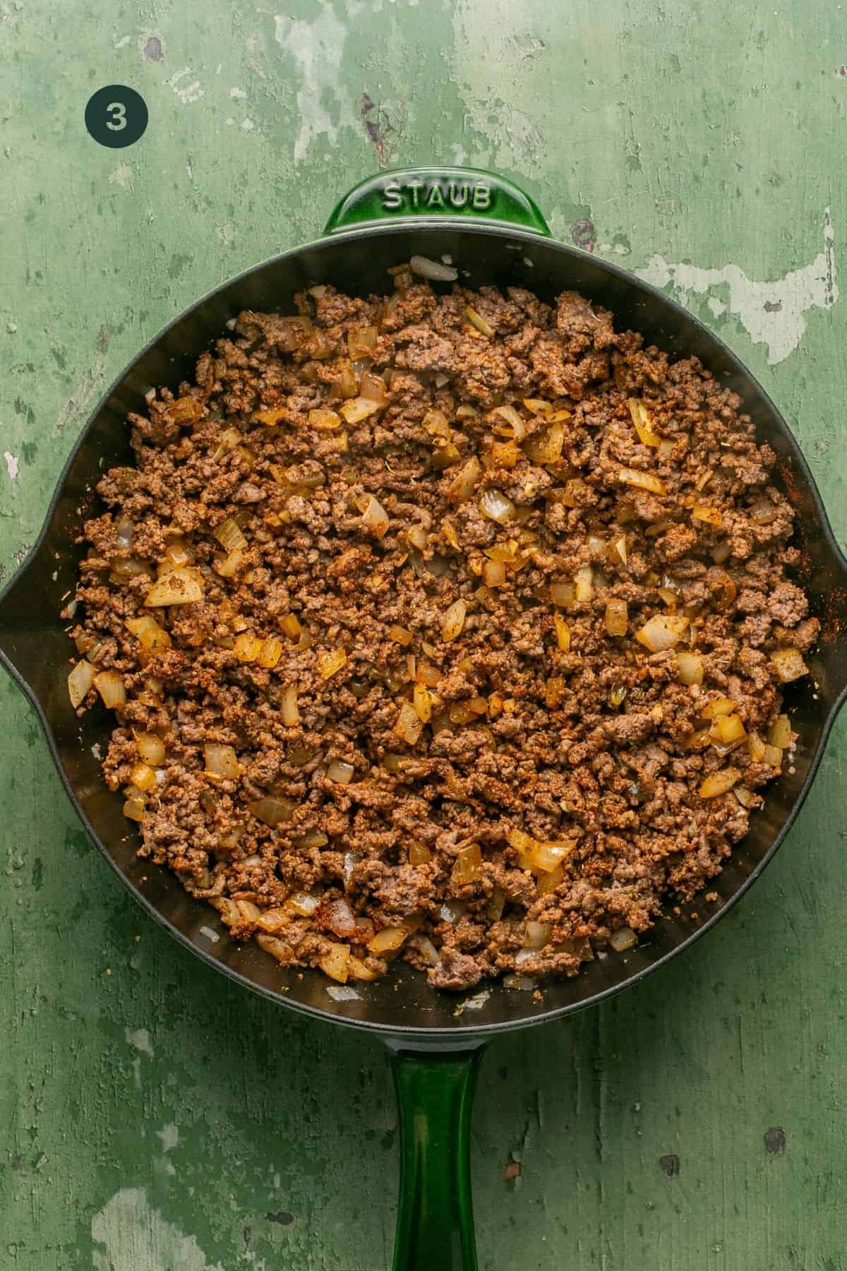 Fully combined meat and onion mixture in a skillet. 