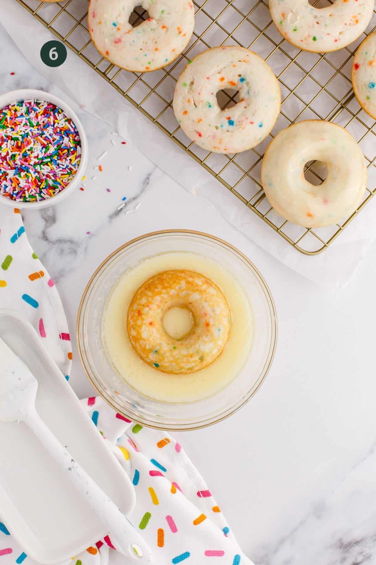 One donut upside down in a bowl of frosting.