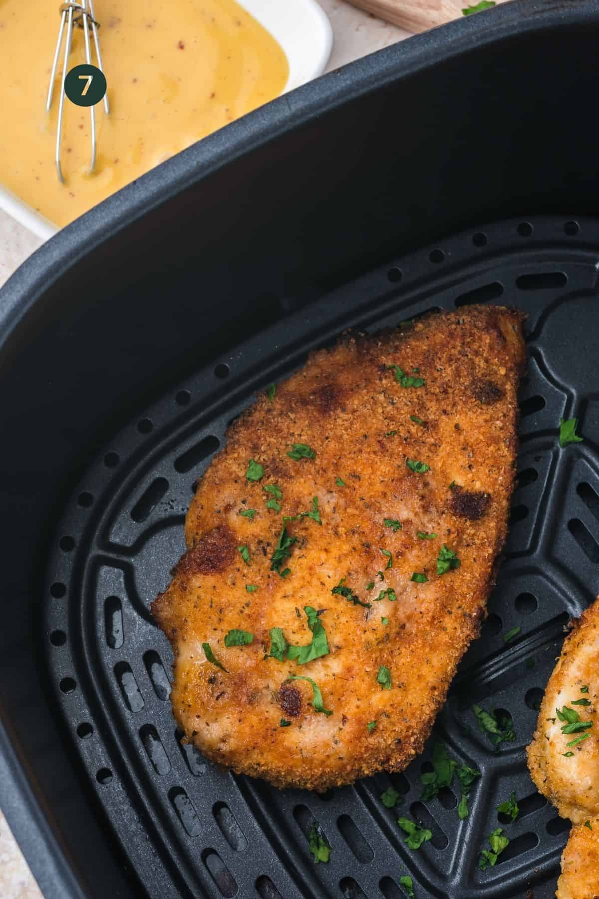 Cooked breaded chicken breast in the air fryer basket.