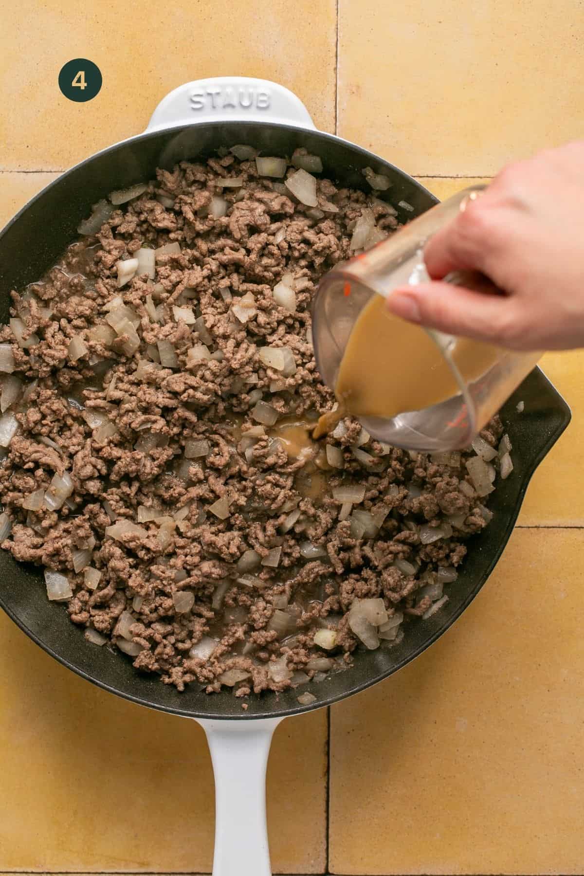 Broth added to ground beef mixture in the pan.