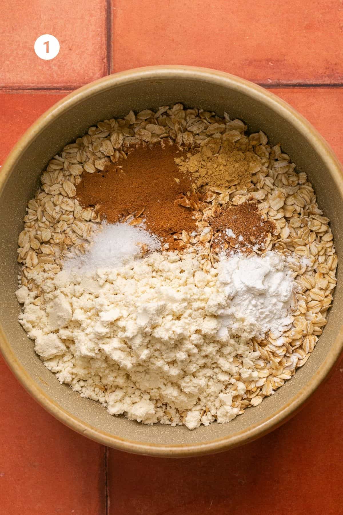Oats, baking powder, cinnamon, nutmeg, cloves, salt and protein powder in a mixing bowl. 