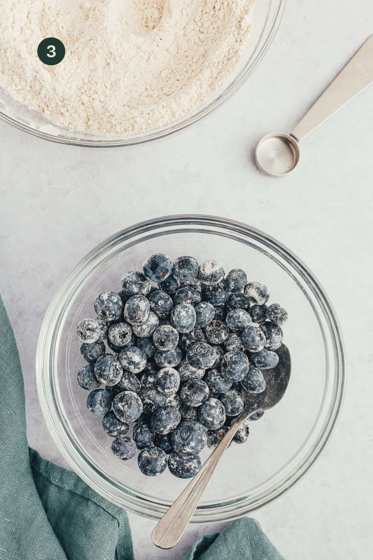 Fresh blueberries in a bowl coated lightly with flour. 