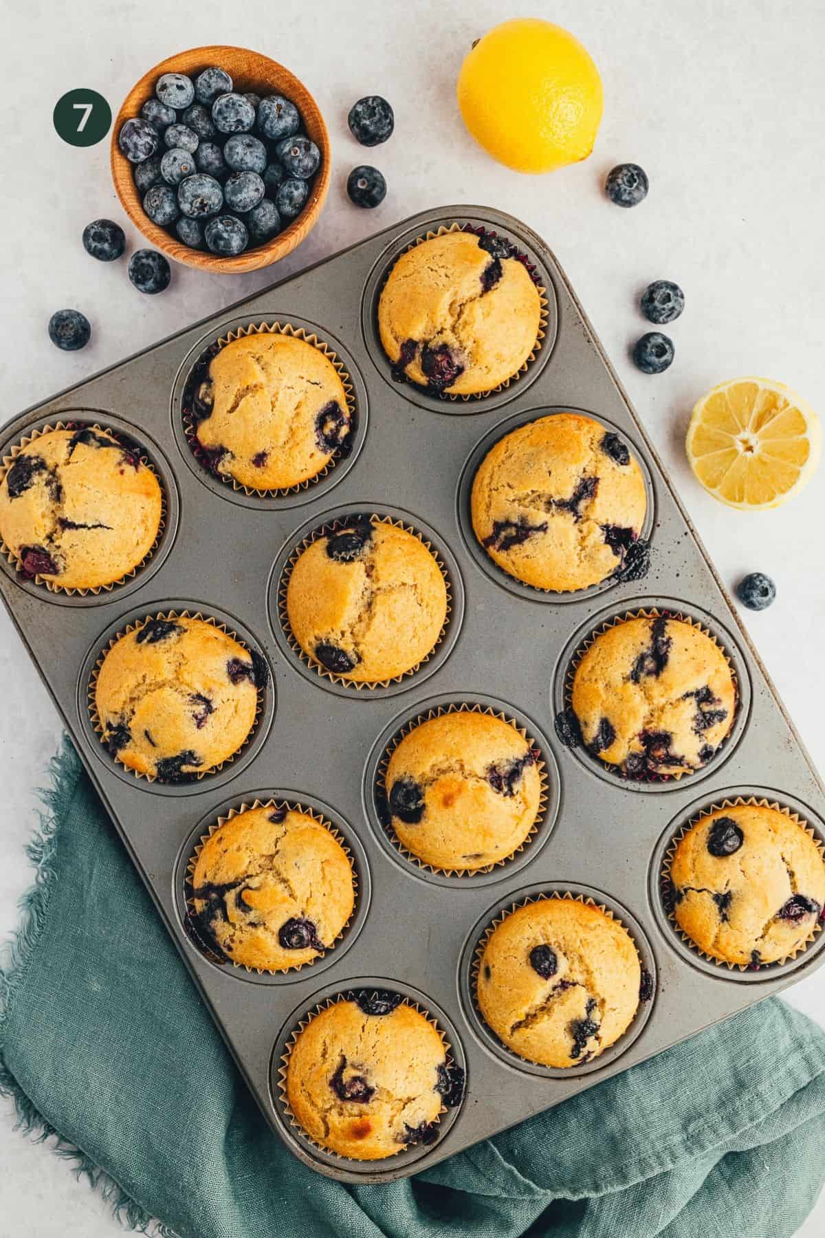 Fully baked blueberry lemon muffins in a muffin pan cooling. 