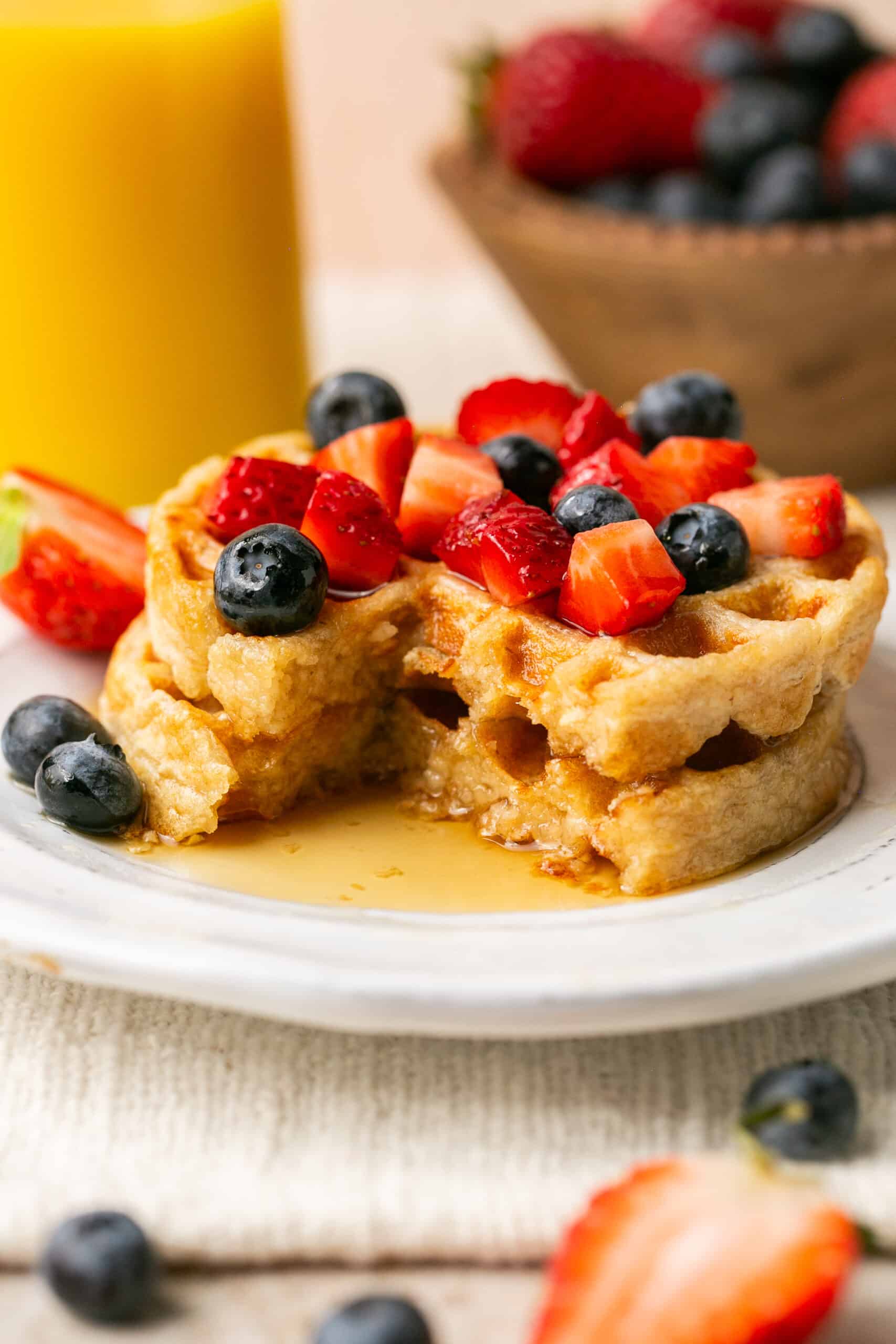 2 waffles stacked with berries and syrup on top.