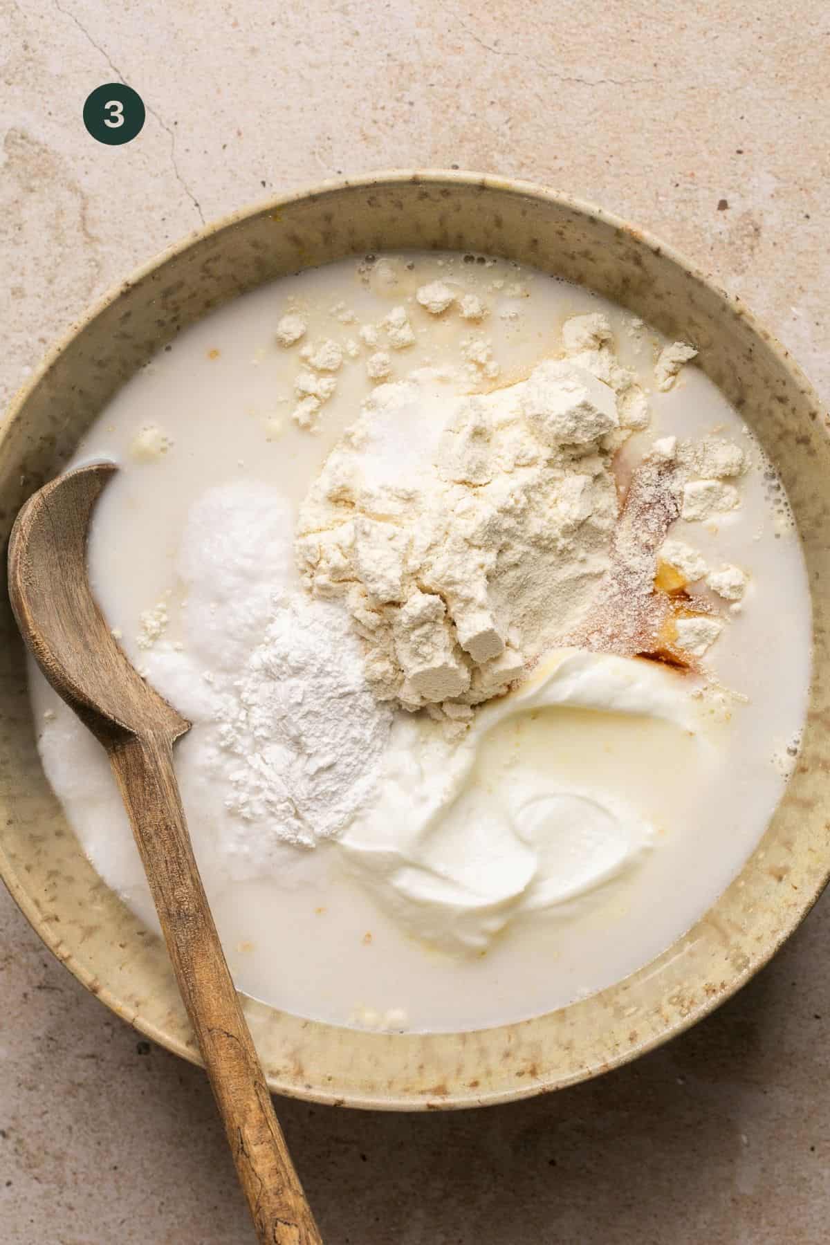 Baking powder, almond milk, egg whites, oats, honey, protein powder and salt added to a bowl.