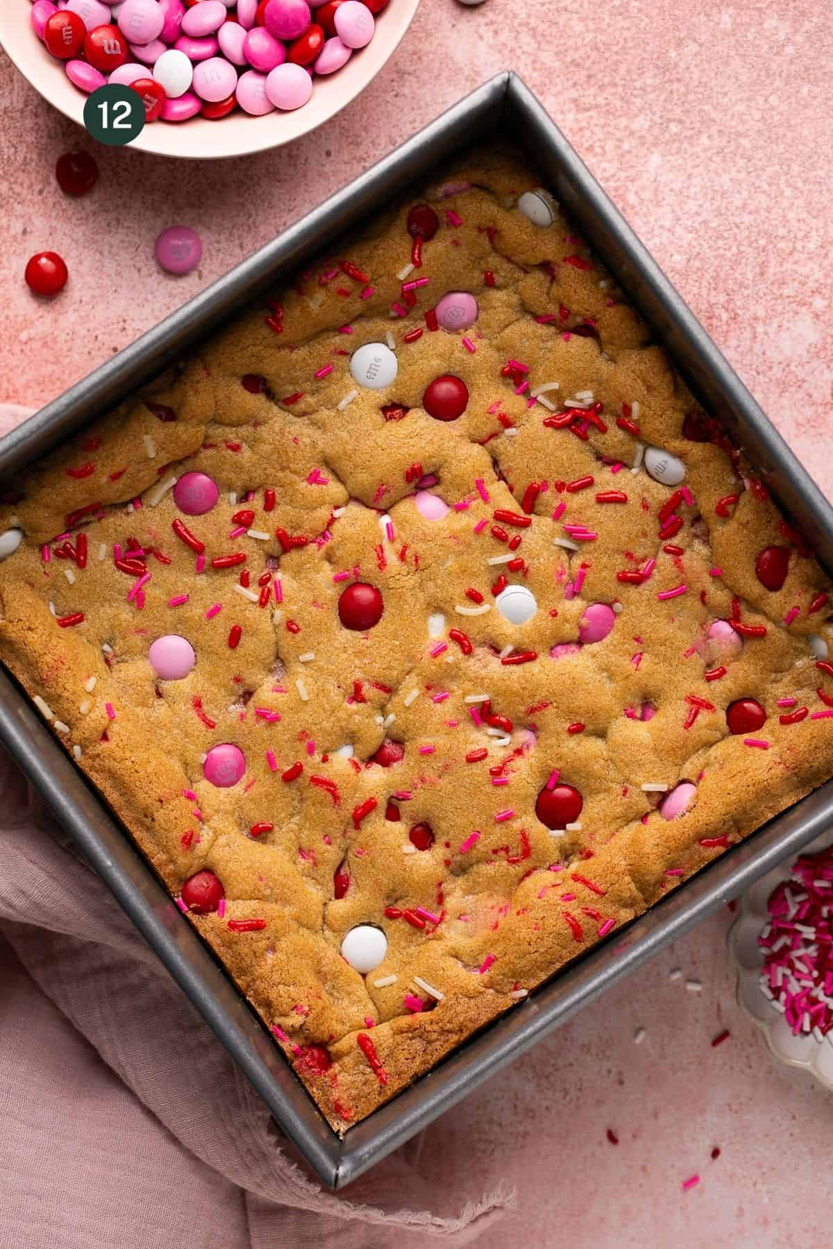 Fully baked cookie bars with sprinkles and M&M's on top and on the sides of the dish.