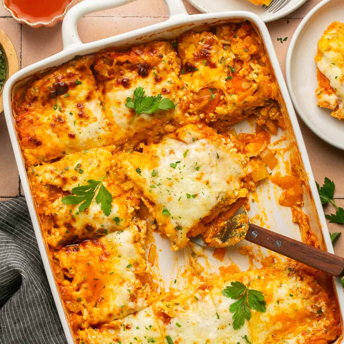 Cheesy baked lasagna with a serving utensil pulling out a serving.