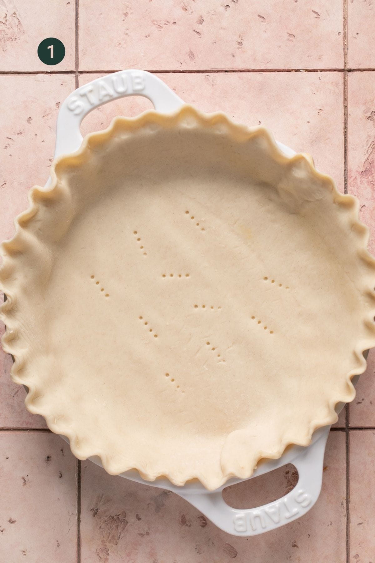 Pie crust with holes poked in the center in a pie dish. 