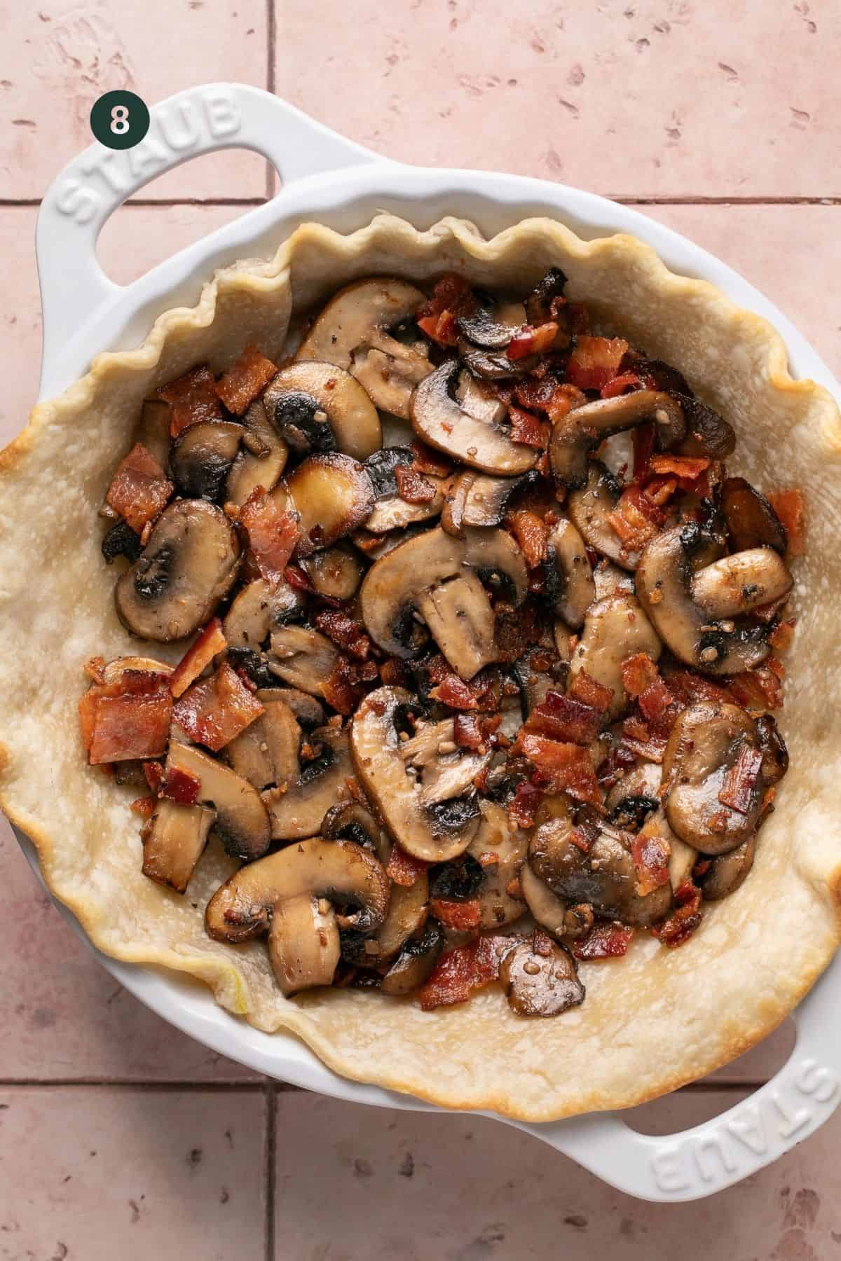 Cooked mushrooms and bacon added to the pre cooked pie crust in a  pie dish. 