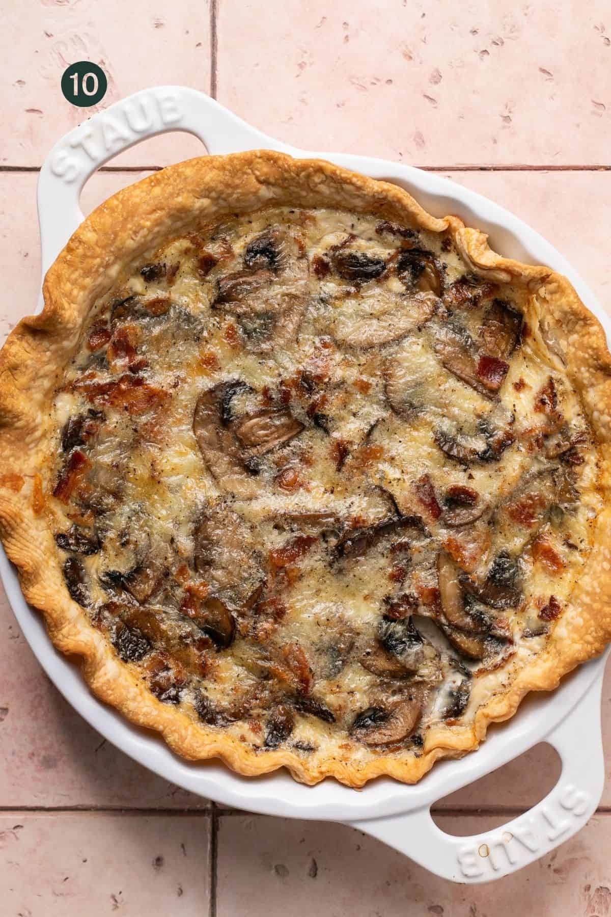 Freshly baked egg white quiche with mushrooms and bacon throughout in a pie dish. 