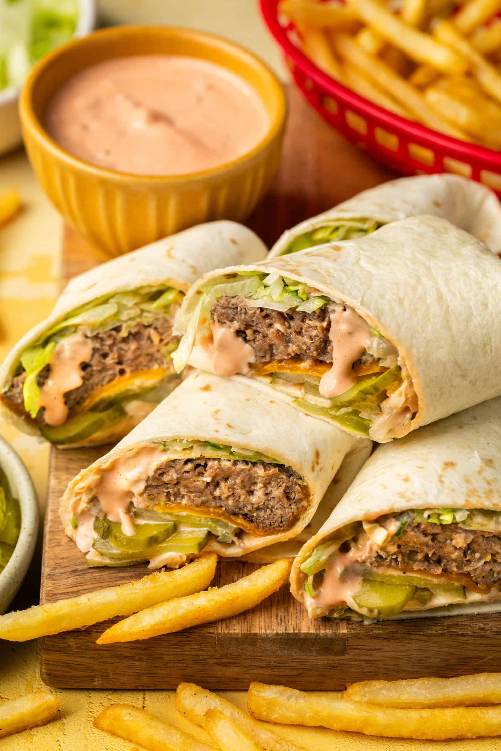 Four wraps filled with cooked burgers, lettuce, cheese, pickles and Big Mac sauce with a side of fries.