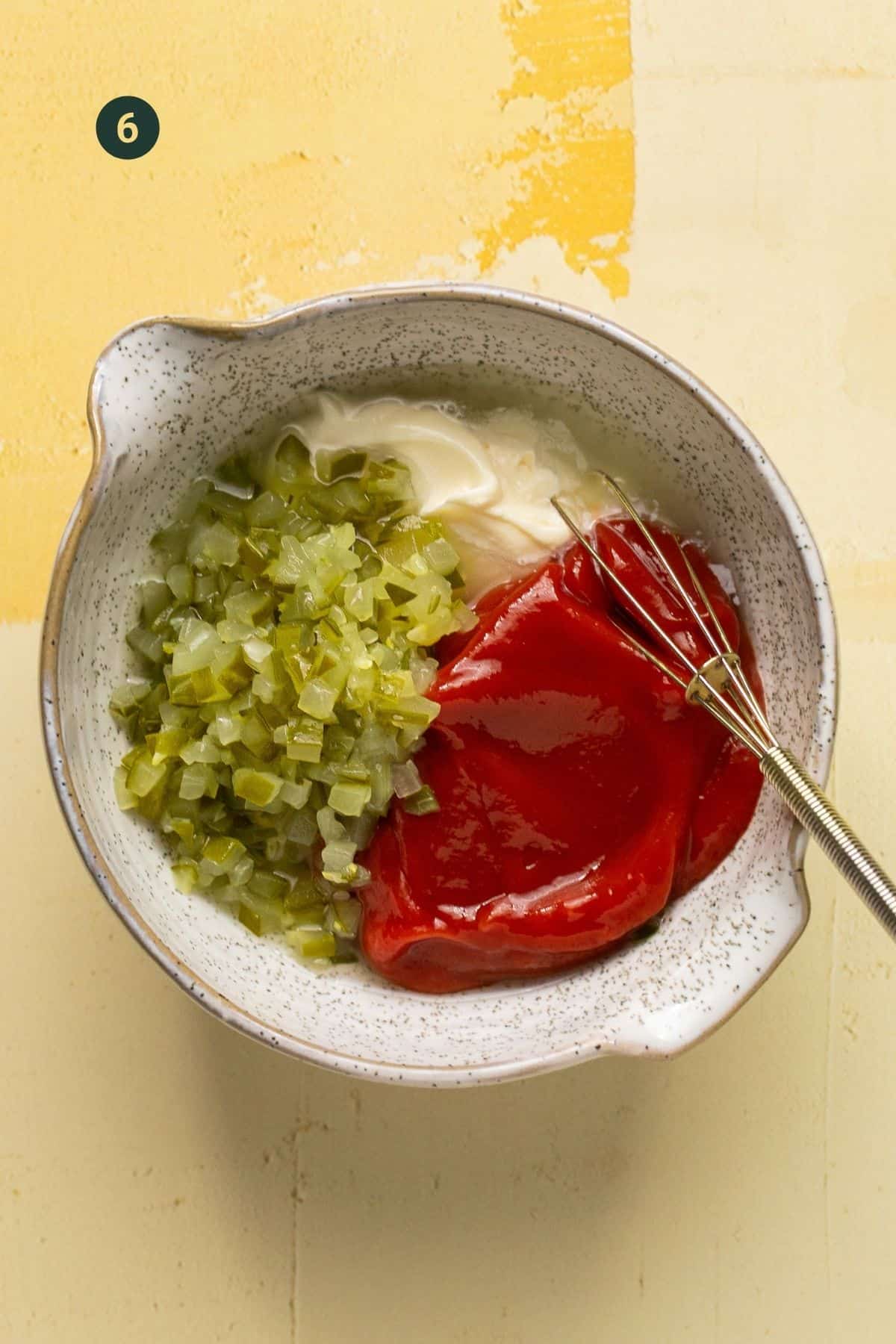 Mayonnaise, ketchup, dill pickle juice and chopped dill pickles in a mixing bowl with a whisk. 