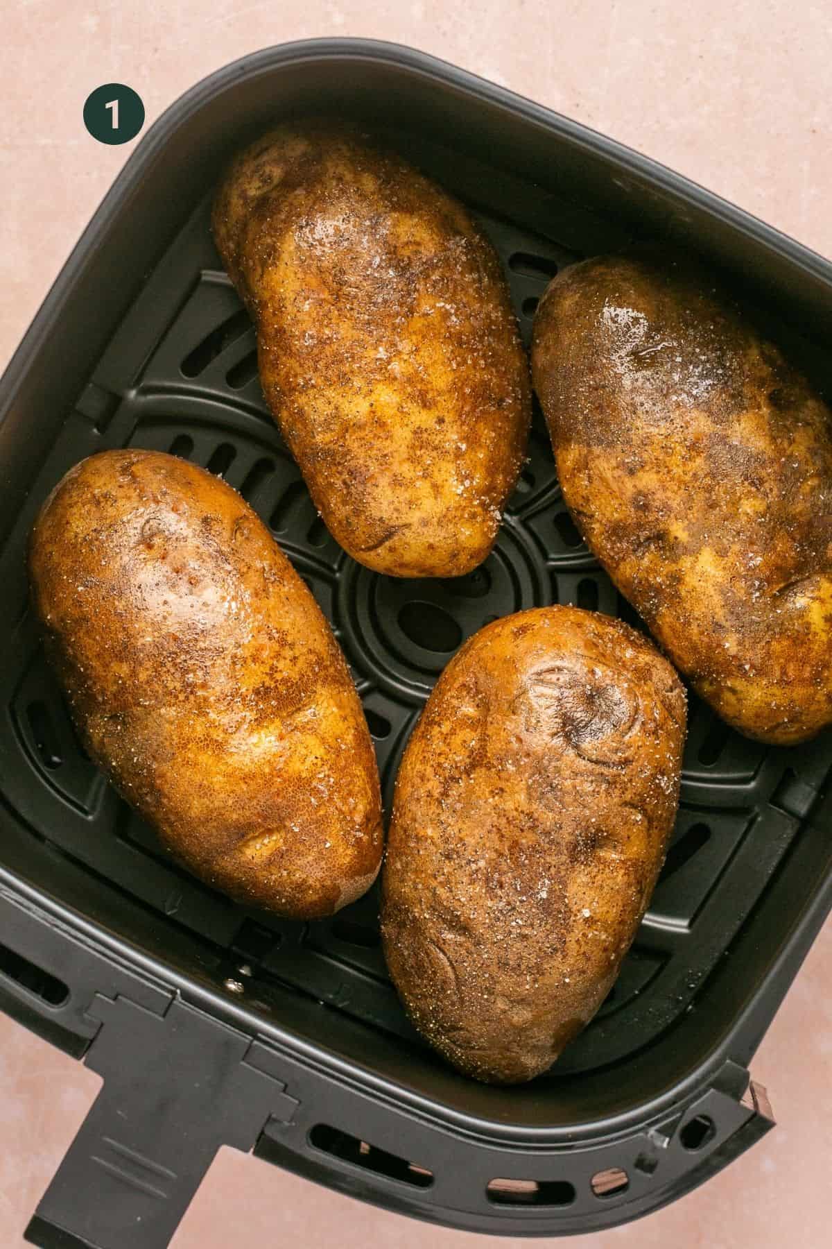 Four russet potatoes in the basket of a air fryer. 