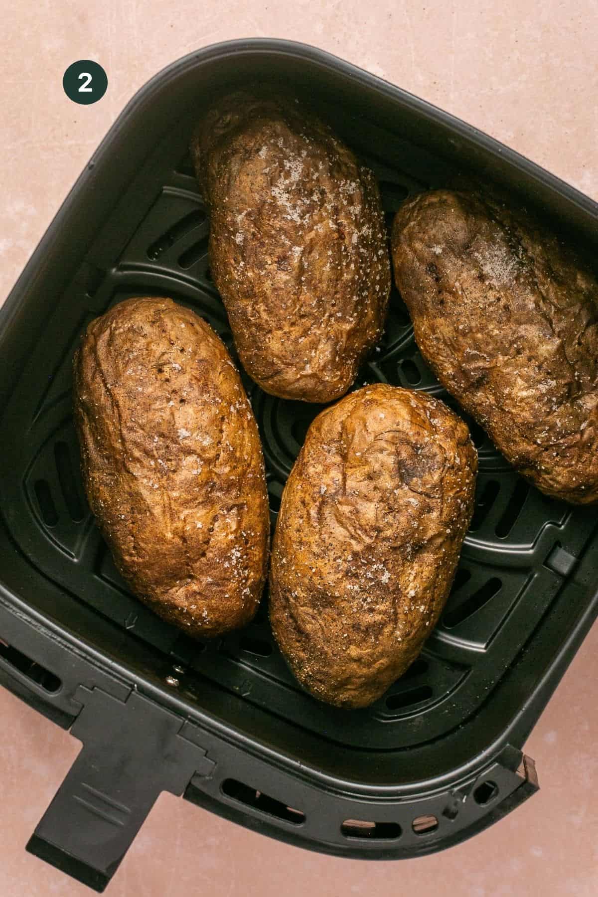 Four wrinkly potatoes in a air fryer basket fully baked. 