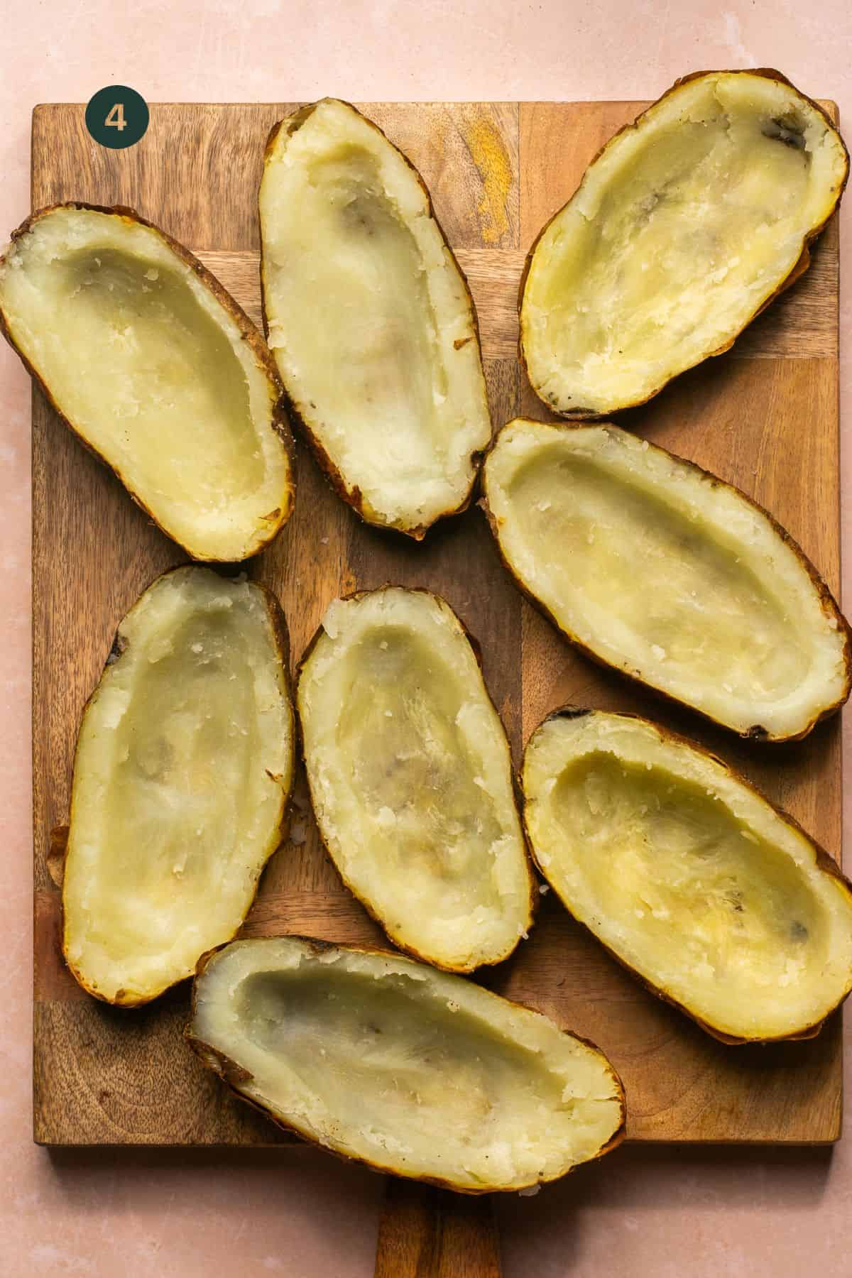 Baked potatoes with the centers scooped out leaving only the skins on a cutting board.